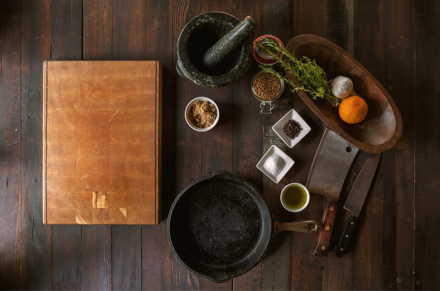 Mortar and pestle with dried herbs, rosemary, and botanicals on dark wood